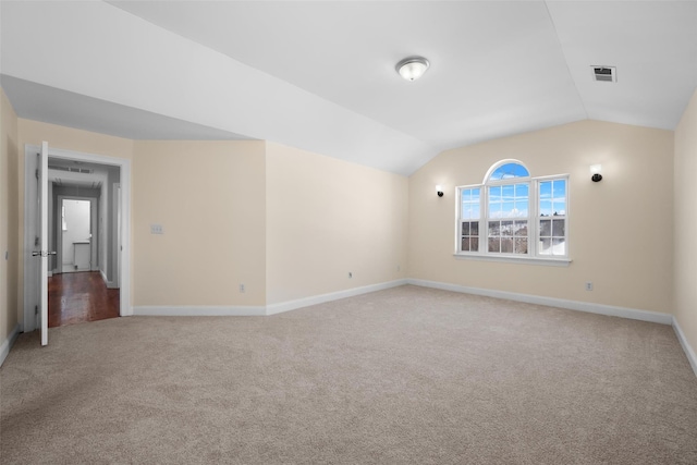 carpeted empty room with vaulted ceiling