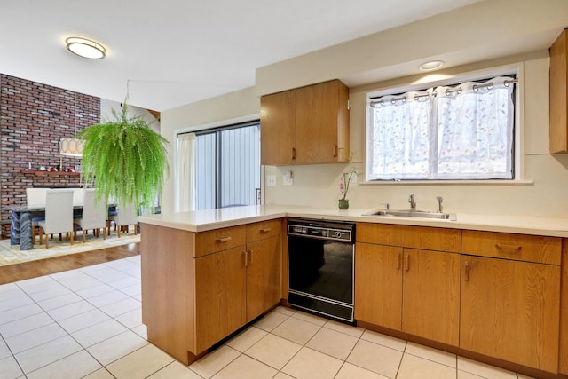 kitchen with sink, black dishwasher, brick wall, light tile patterned flooring, and kitchen peninsula