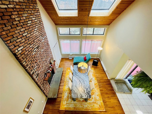 living room featuring hardwood / wood-style flooring, wooden ceiling, high vaulted ceiling, and a skylight