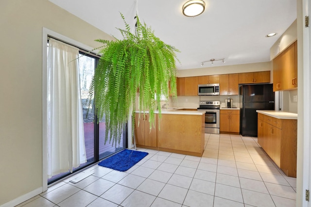 kitchen with sink, light tile patterned floors, track lighting, appliances with stainless steel finishes, and kitchen peninsula