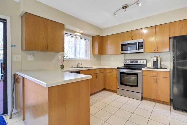 kitchen with light tile patterned flooring, sink, track lighting, appliances with stainless steel finishes, and kitchen peninsula