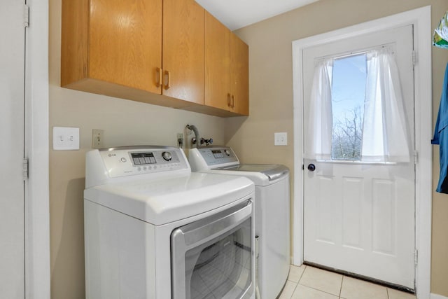 clothes washing area featuring a wealth of natural light, cabinets, washing machine and clothes dryer, and light tile patterned flooring