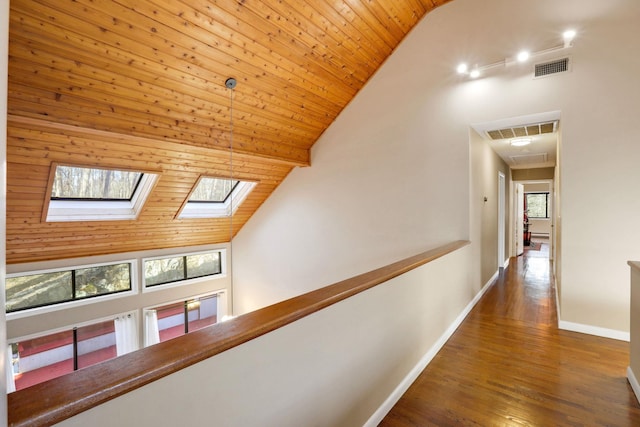 hallway featuring a healthy amount of sunlight, dark wood-type flooring, wooden ceiling, and high vaulted ceiling