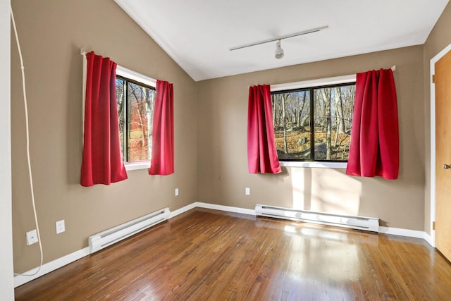 empty room featuring lofted ceiling, a baseboard heating unit, wood-type flooring, and track lighting