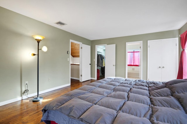 bedroom with a closet, ensuite bath, dark hardwood / wood-style floors, and a spacious closet