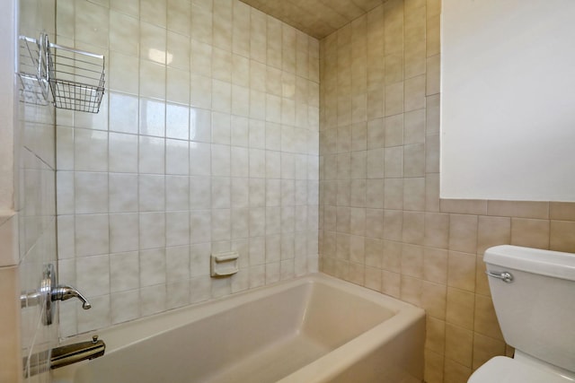 bathroom featuring tiled shower / bath, tile walls, and toilet