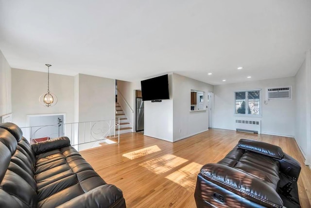 living room with radiator, a wall unit AC, an inviting chandelier, and light hardwood / wood-style floors