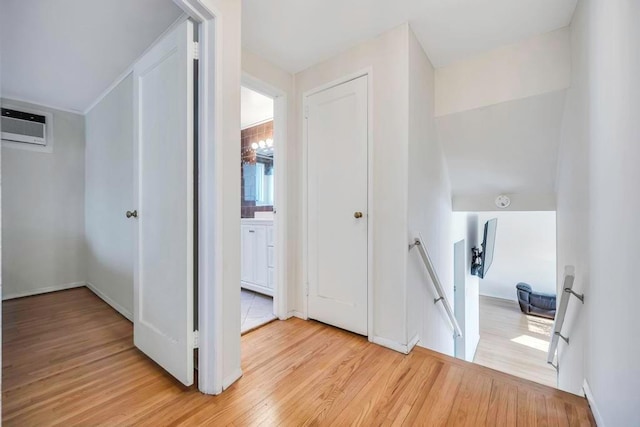 hall featuring a wall unit AC and light wood-type flooring