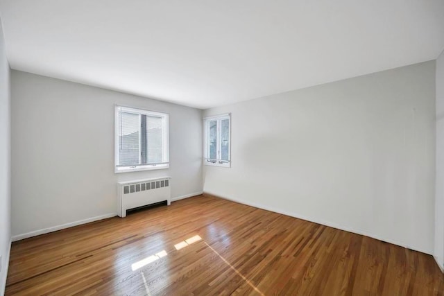 unfurnished room with radiator heating unit and light hardwood / wood-style flooring