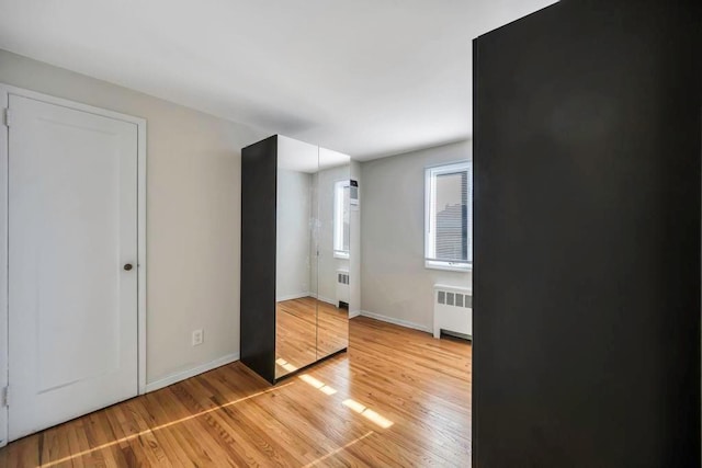 unfurnished bedroom featuring radiator and light wood-type flooring