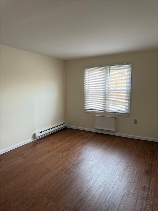 spare room with baseboard heating and dark wood-type flooring