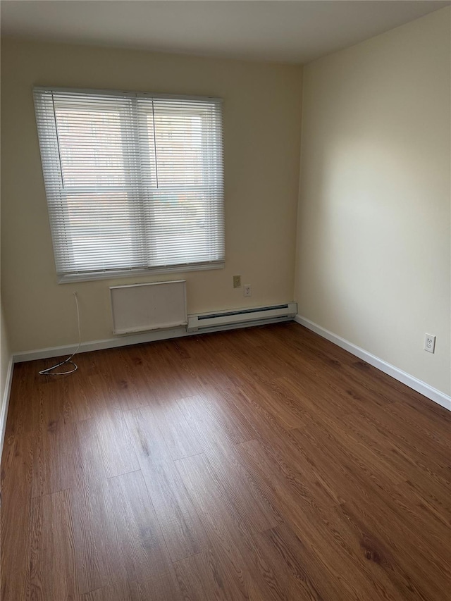 empty room with wood-type flooring and a baseboard radiator