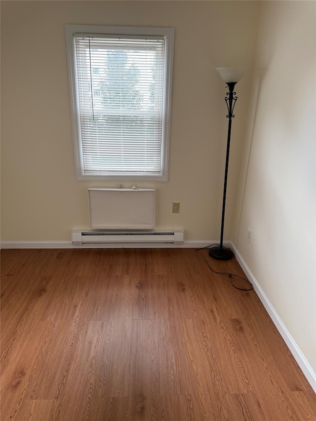 spare room with a baseboard heating unit and light hardwood / wood-style flooring