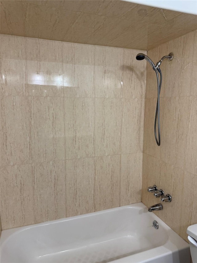 bathroom featuring toilet and tiled shower / bath combo