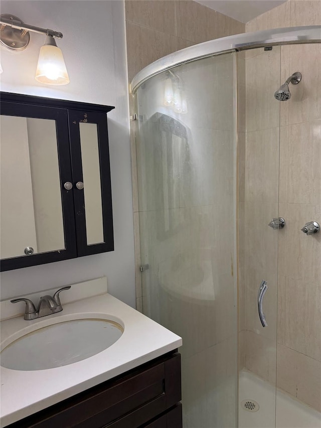 bathroom featuring a shower with shower door and vanity