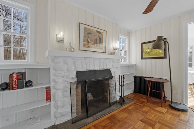 details with radiator heating unit, parquet flooring, a fireplace, ornamental molding, and ceiling fan