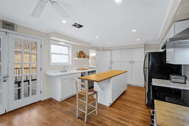 kitchen with a center island, white cabinetry, sink, a kitchen breakfast bar, and light hardwood / wood-style flooring