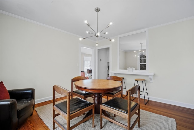 dining space with hardwood / wood-style floors, a notable chandelier, and ornamental molding