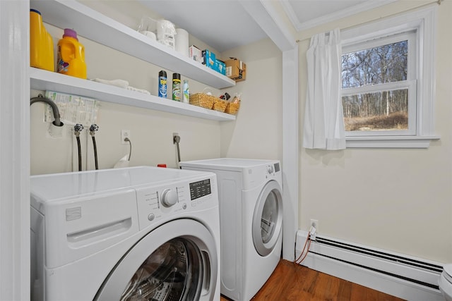 clothes washing area with dark wood-type flooring, baseboard heating, crown molding, and washing machine and clothes dryer