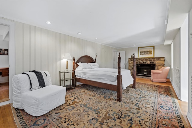 bedroom with hardwood / wood-style floors, ornamental molding, and a fireplace