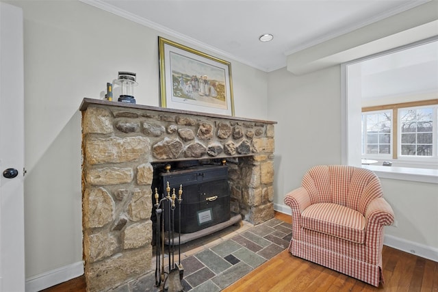 sitting room featuring dark hardwood / wood-style floors, crown molding, and a stone fireplace