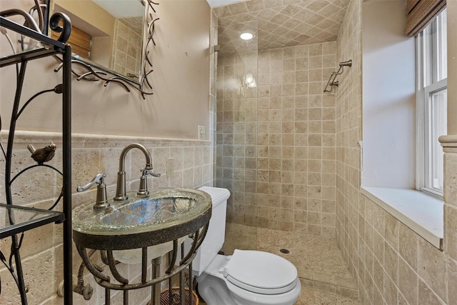 bathroom with tiled shower, toilet, and tile walls