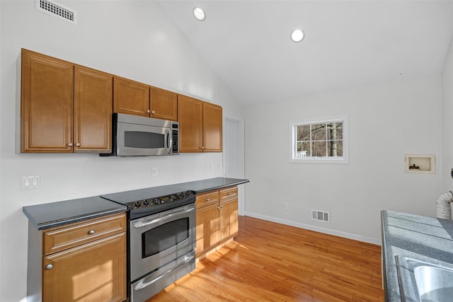 kitchen with light hardwood / wood-style floors, high vaulted ceiling, and appliances with stainless steel finishes