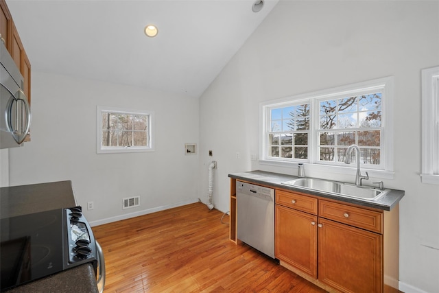 kitchen featuring sink, stainless steel appliances, light wood-type flooring, and lofted ceiling