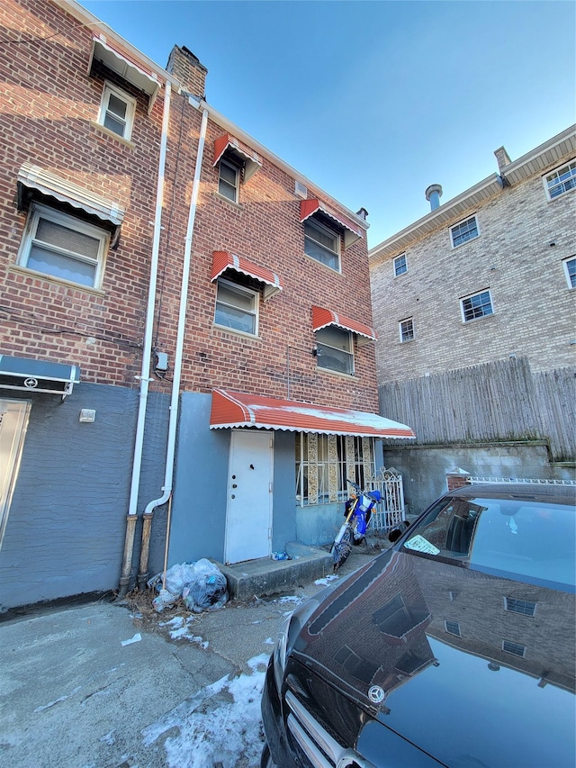 rear view of property with brick siding and fence