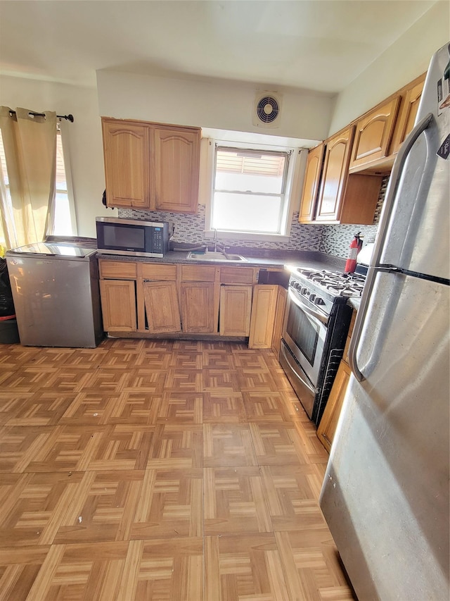 kitchen with backsplash, visible vents, appliances with stainless steel finishes, and a sink