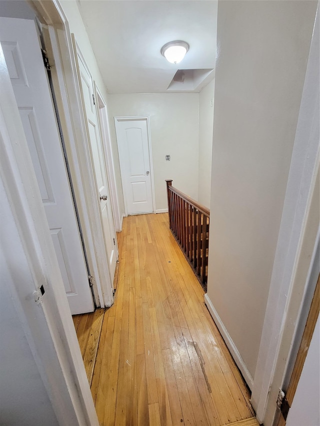 hallway featuring an upstairs landing, light wood-style floors, and baseboards