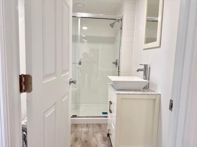 bathroom featuring a shower with shower door, hardwood / wood-style flooring, and vanity