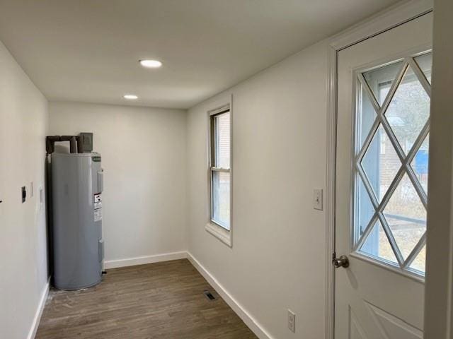 doorway to outside featuring dark wood-type flooring, water heater, and a healthy amount of sunlight