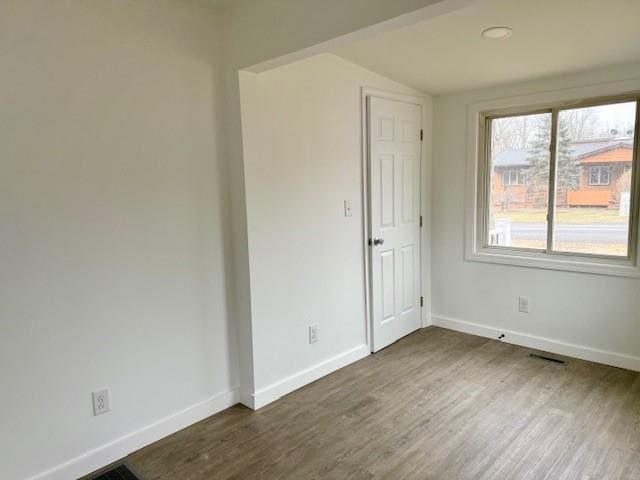 empty room featuring vaulted ceiling and dark hardwood / wood-style floors