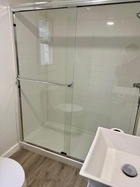 bathroom featuring wood-type flooring, an enclosed shower, and toilet