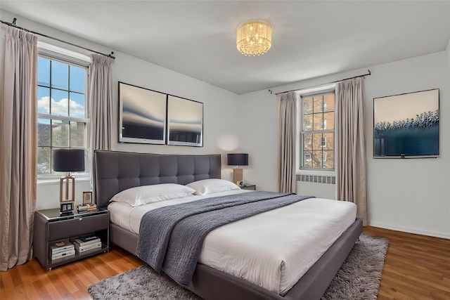 bedroom with radiator heating unit and wood-type flooring