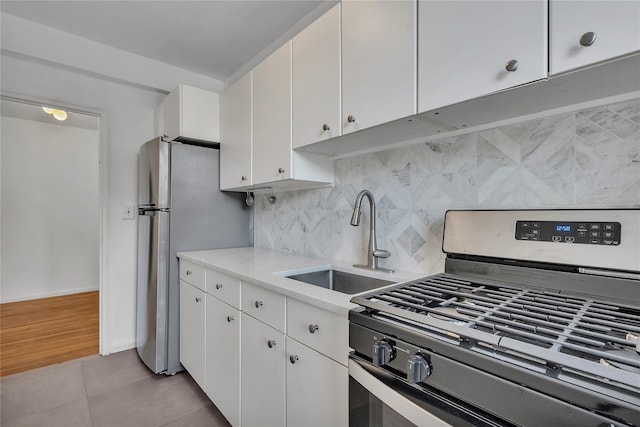 kitchen with sink, light tile patterned flooring, white cabinets, and appliances with stainless steel finishes