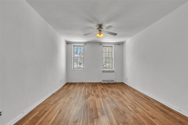 empty room featuring ceiling fan, radiator heating unit, and light wood-type flooring