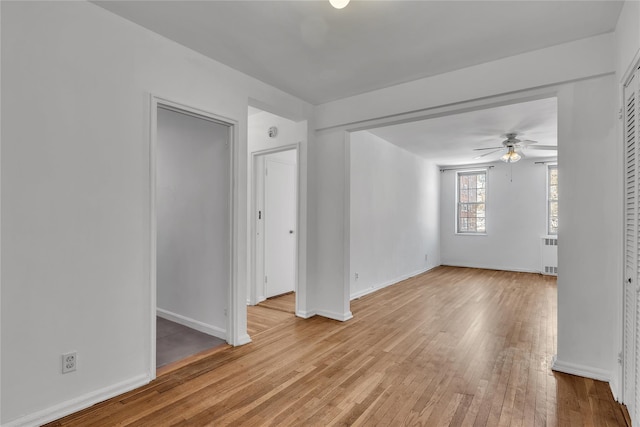 empty room with light hardwood / wood-style floors, radiator heating unit, and ceiling fan