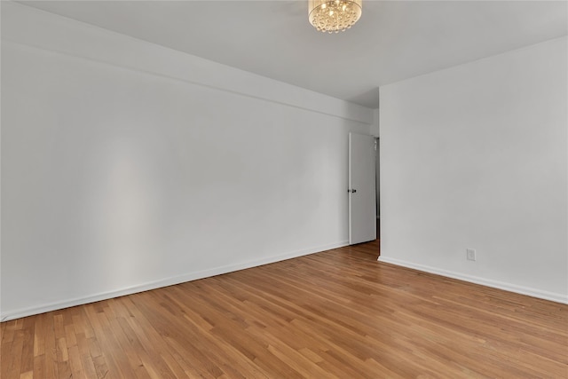 empty room with light wood-type flooring and an inviting chandelier