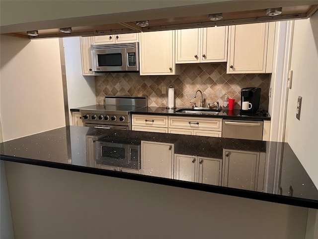 kitchen featuring appliances with stainless steel finishes, white cabinets, dark stone counters, sink, and backsplash