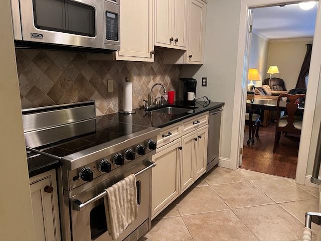 kitchen featuring light tile patterned floors, decorative backsplash, sink, white cabinets, and stainless steel appliances