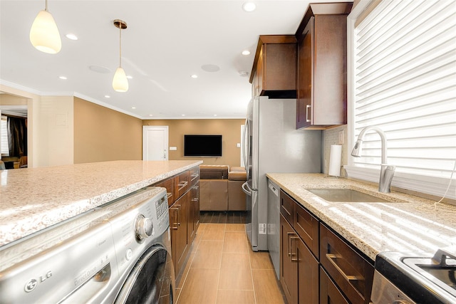 kitchen featuring light stone countertops, washer / dryer, sink, and pendant lighting