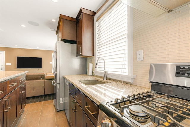 kitchen featuring sink, crown molding, stainless steel appliances, dark brown cabinetry, and light stone countertops