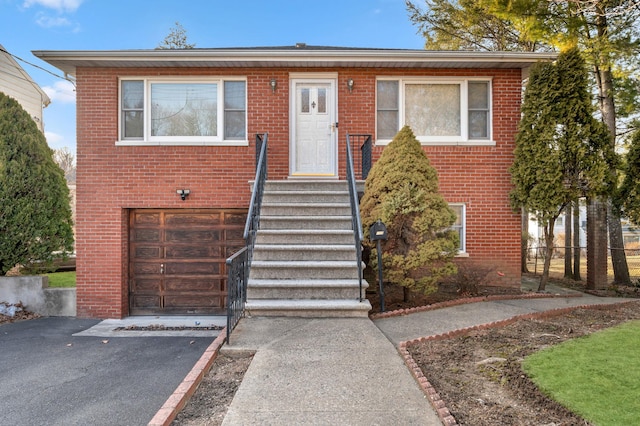 view of front facade featuring brick siding, aphalt driveway, and a garage