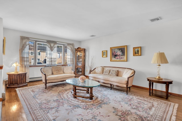 living room featuring hardwood / wood-style flooring, baseboards, visible vents, and a baseboard radiator