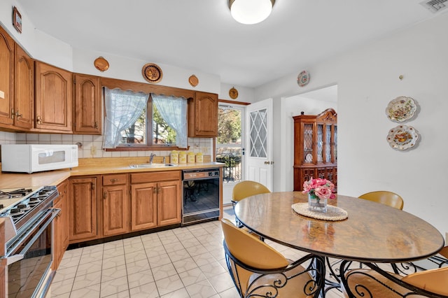 kitchen featuring visible vents, a sink, black dishwasher, stainless steel range with gas cooktop, and white microwave