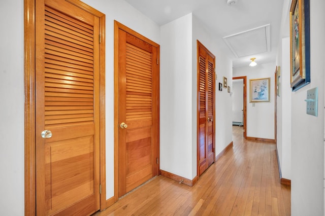 hall featuring light wood finished floors, attic access, a baseboard heating unit, and baseboards