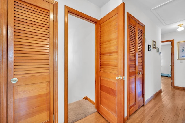 hall with light wood-style flooring and baseboards