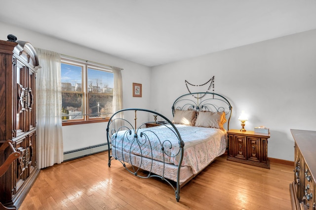 bedroom featuring a baseboard heating unit, baseboards, light wood-style floors, and a view of city